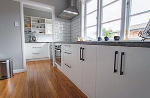 Kitchen remodel showcasing white cabinets and new laminate flooring.