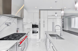 Ultra-modern, all-white kitchen design with large format tiles and granite accents.