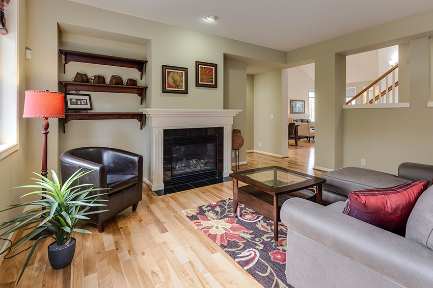 Laminate flooring in the living room of a Portland bungalow with a white fireplace.