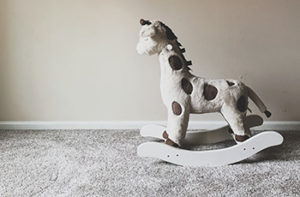 A child's rocking horse sits on plush gray carpet