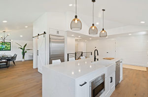 Wood-like laminate flooring in a light color has been installed in a kitchen and dining room for a seamless, classic look.