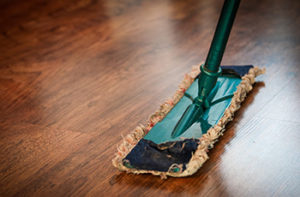 Close up of a traditional mop on dark, wood-like looking vinyl flooring