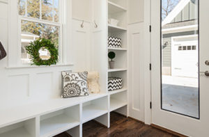 Waterproof wood-like vinyl flooring is in a small mudroom with white built-in cabinets and bench.