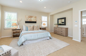 A plush white area rug has been placed on beige carpet in a bedroom, which creates a warm and welcoming look