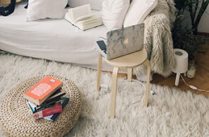 A white shag area rug is next to a white couch where a laptop is open on the table next to it.