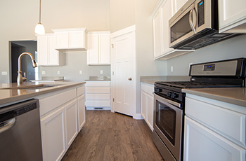 The dark hardwood flooring in this kitchen contrasts beautifully with the bright, white cabinets and stainless steel appliances.