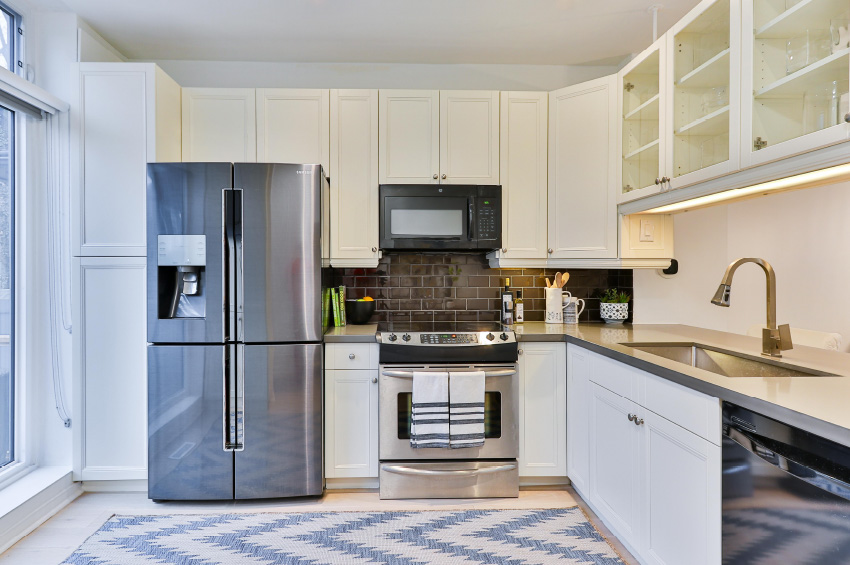 Blue and white area rug in a remodeled kitchen with white cabinets and grey stone-looking countertops