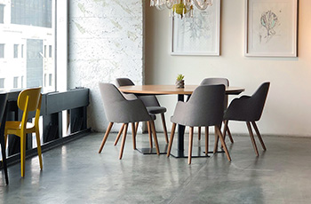 Office building has a dark, polished concrete floor with small wood meeting table and four chairs.