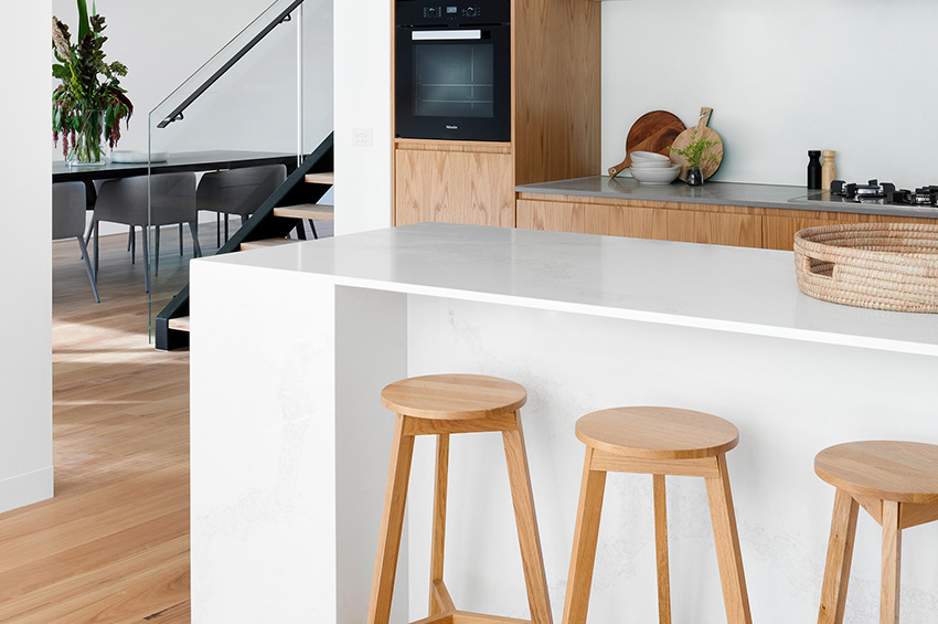 White kitchen island with light oak barstools and hardwood flooring.