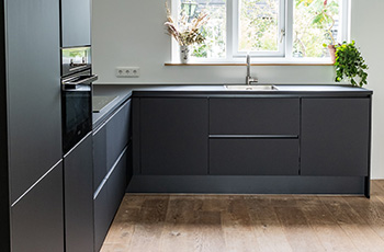 Dark hardwood flooring in a kitchen with grey cabinets.