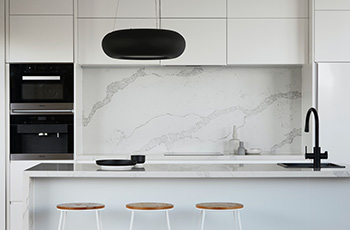 White kitchen countertop with white backsplash and cabinets.