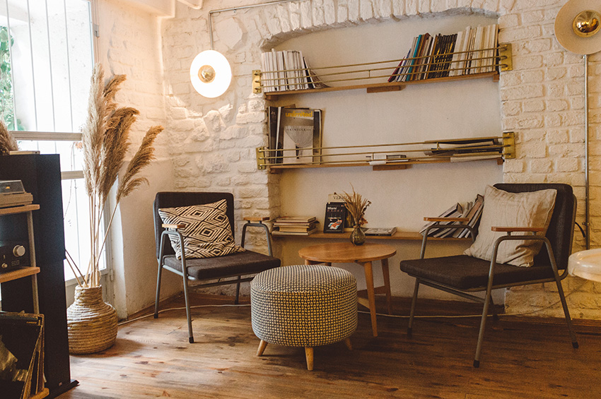 Plank hardwood flooring in a rustic home library, with bookshelves, two chairs, and table.