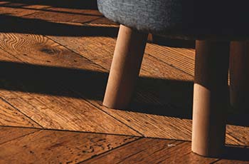 Hardwood floors in a herringbone patter on which a stool sits.