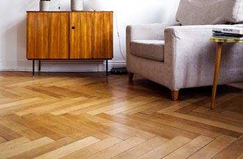 New hardwood flooring in a living room that has been placed in a herringbone pattern.