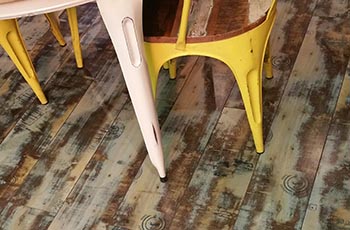 Distressed hardwood flooring under a white table.