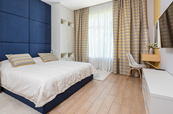 Bamboo flooring in a master bedroom with large window and beige window treatments.