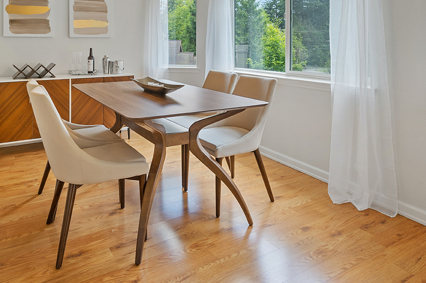 Warm-toned bamboo floors in a dining room with mid-century modern dining room table and chairs.