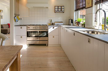Light-colored bamboo floors in a bright and airy kitchen with granite countertops and white cabinets.