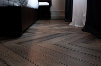 Dark, hardwood floors form a zigzag pattern in a bedroom.