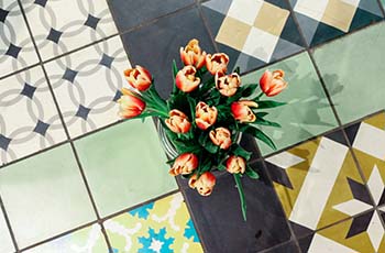 Colorful, virant, and uniquely patterned tile floors showcase a bouquet of orange roses.