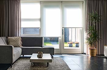 Modern living room includes three windows with Hunter Douglas blinds and curtains.