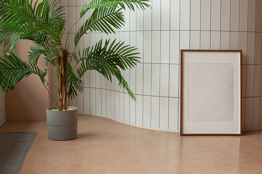 Warm beige colored large format tile flooring has a plant and area rug on it.
