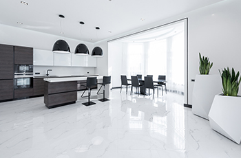 White marble floor tiles in a chic, modern kitchen with black matte cabinets and marble countertop.