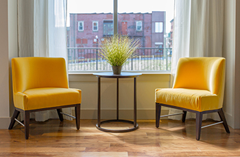 Bright yellow chairs sit next to a window on bamboo flooring.