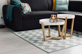 A chevron patterned area rug rests on beachy luxury vinyl plank flooring.