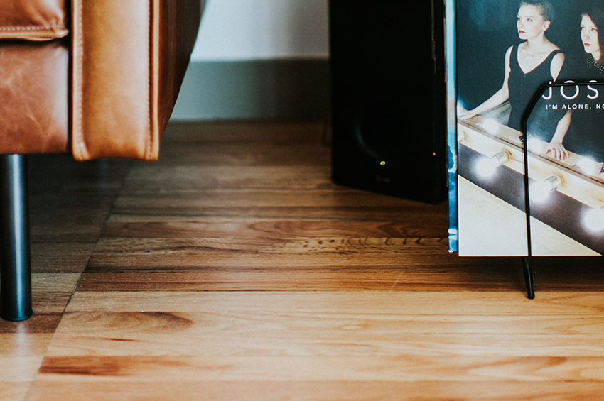 Close up of a leather couch placed on wood-look vinyl flooring.