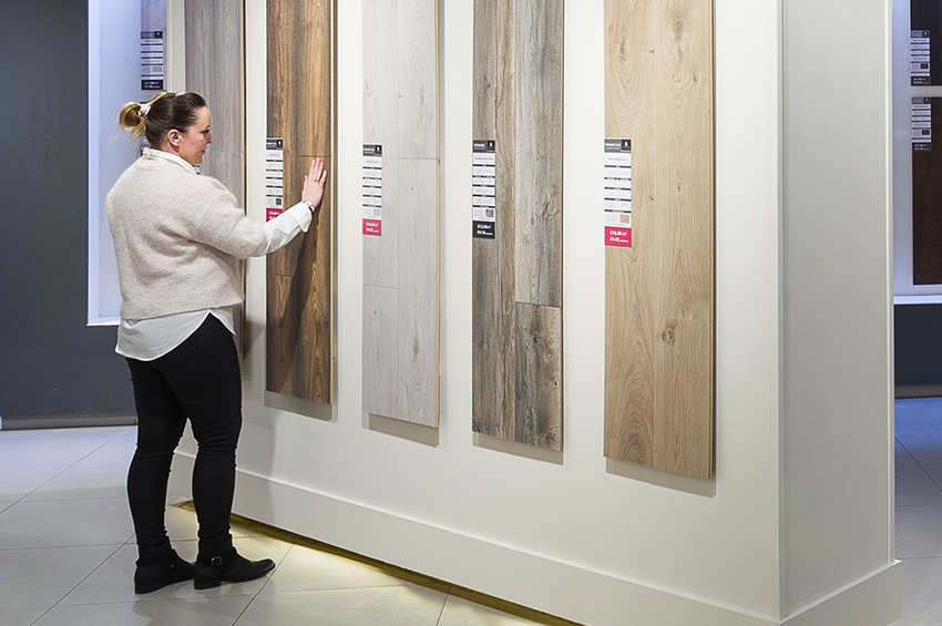 Woman in flooring showroom looking at different types of luxury vinyl plank flooring.