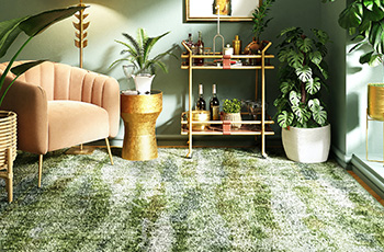 A bright green area rug showcases the glam style of this living room that includes gold end tables and stylish gold bar cart.