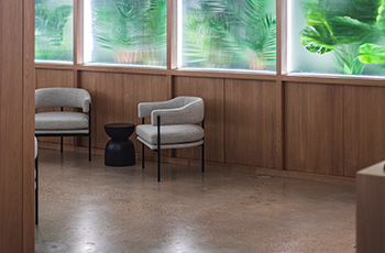 Polished concrete floors in a waiting room with two chairs and frosted glass windows.