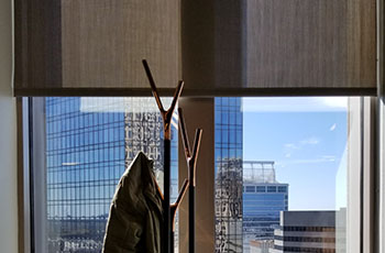 A coat rack has been placed in front of a condo window with Hunter Douglas blinds.