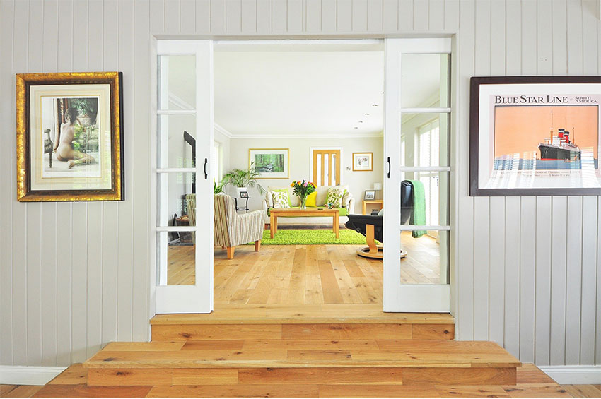 A coastal design inspired living room features hardwood floors, bright green area rug, and brightly colored home decor.