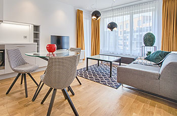 Bright white window sheers and gold curtains and geometric area rug make this small living room come alive with color.