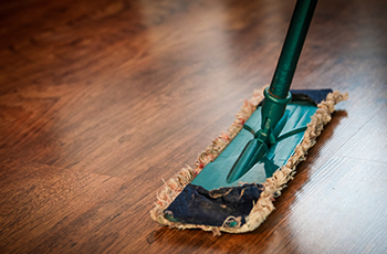Close up shot of a large dry mop on a wood floor.