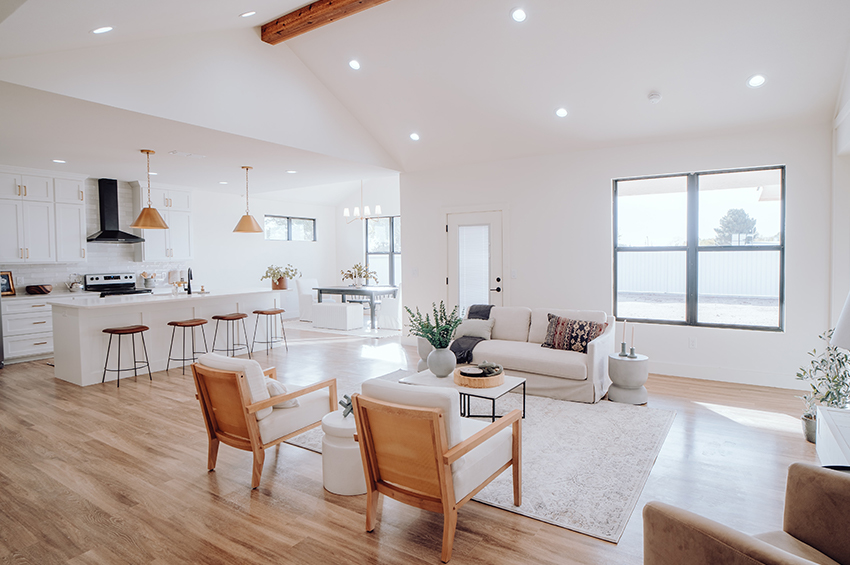 Open concept living room with light wood floors, white furniture, and lots of natural light.