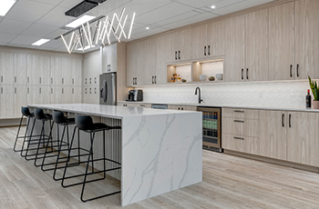 Modern kitchen with ashy vinyl flooring, matching cabinets, and a marble kitchen island.