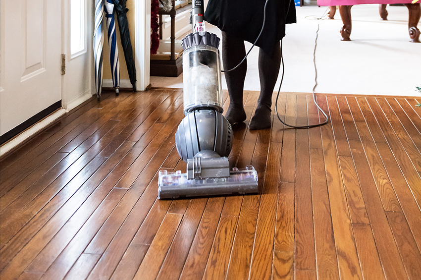 Close up of a modern-looking vacuum against a deep, traditional wood floor.