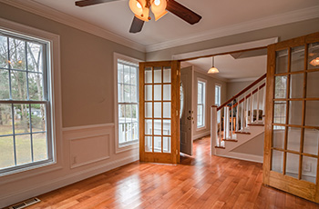 Craftsman living room with rich wood floors, wainscoting trim, and french doors leading to the front entrance.