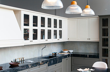 Monochromatic kitchen with off-white cabinets and backsplash and a dark stone countertop.