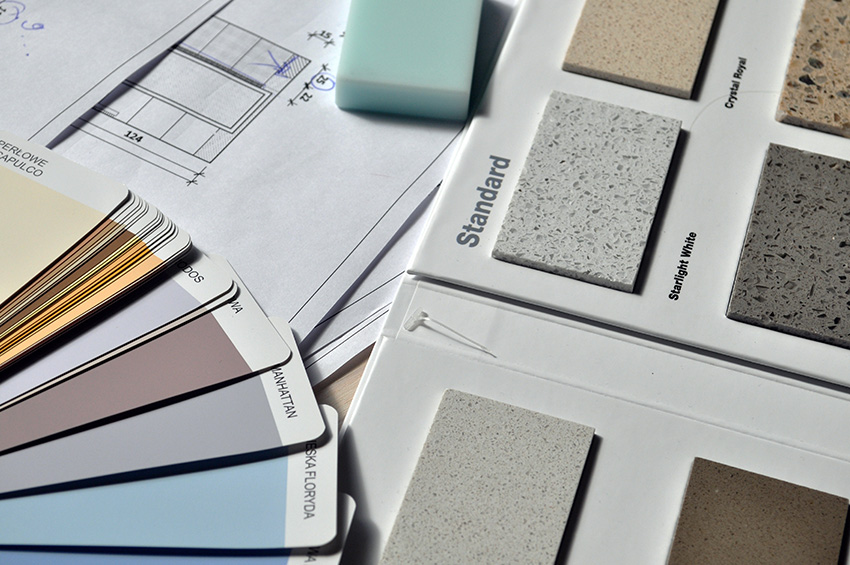Flat lay of renovation materials, including granite samples, blueprints, and a paint fan deck.