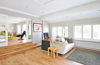 Bright and airy living area with light wood floors and three stairs leading to a recessed den.