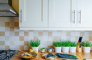 Cheerful kitchen with white cabinets and an oak countertop. The tile is a white and orange check that complements the cabinets and countertop.