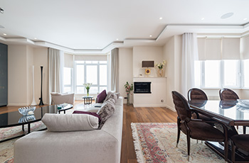 Open concept living and dining space with medium-tone vinyl wood floors and light walls.